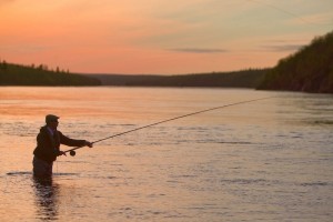 An angler unfurls a spey cast in low light on the Ponoi.