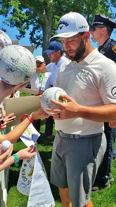 Jon Rahm and Phil Mickelson signing autographs